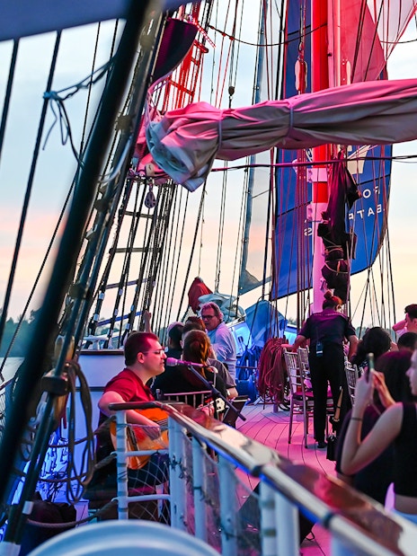 Guests dining on the deck of The Royal Albatross during a sunset cruise.