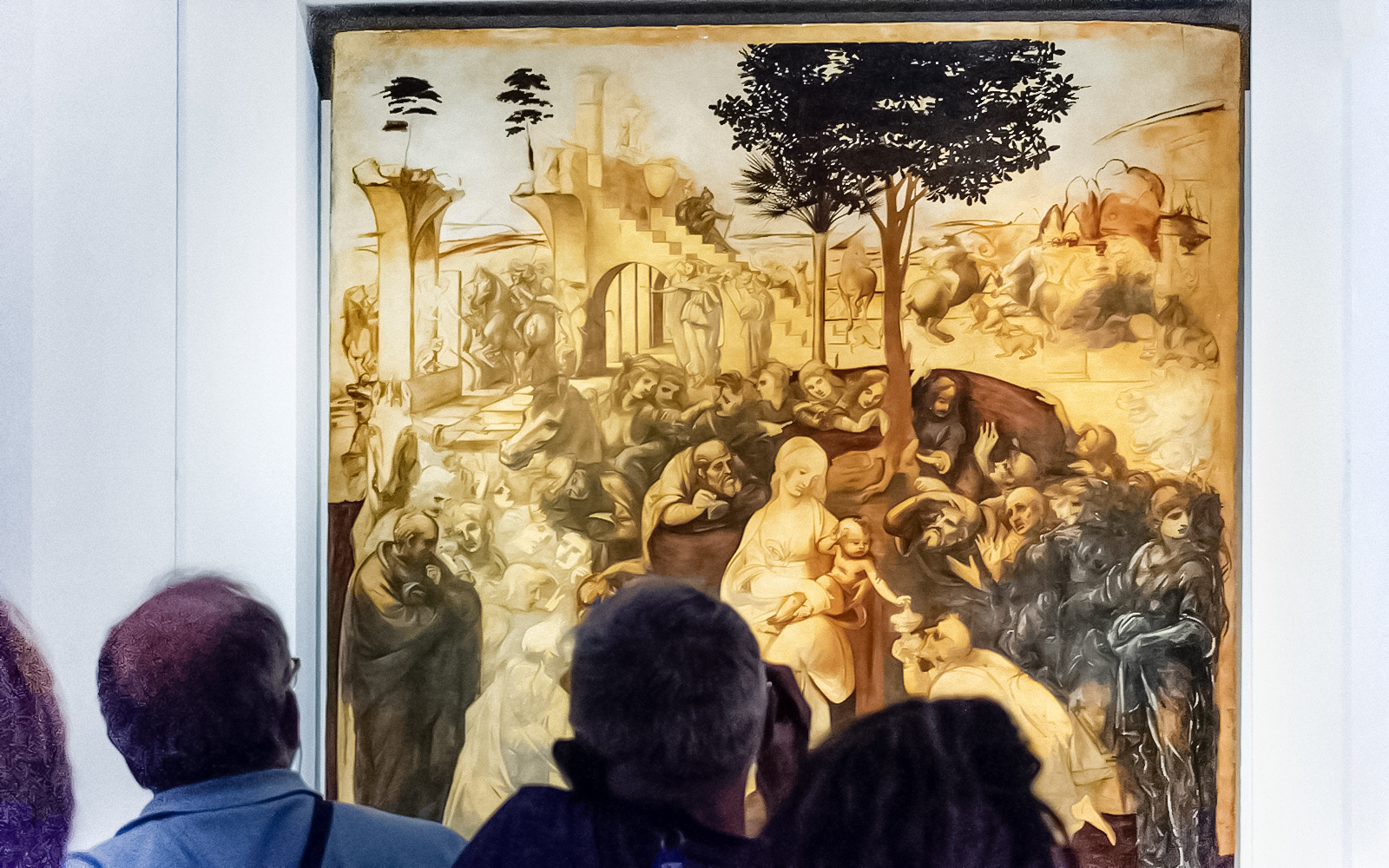 Visitors viewing Leonardo Da Vinci's "Adoration of the Magi" painting in a museum.