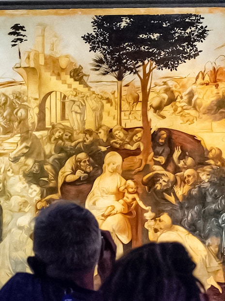 Visitors viewing Leonardo Da Vinci's "Adoration of the Magi" painting in a museum.