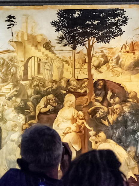 Visitors viewing Leonardo Da Vinci's "Adoration of the Magi" painting in a museum.