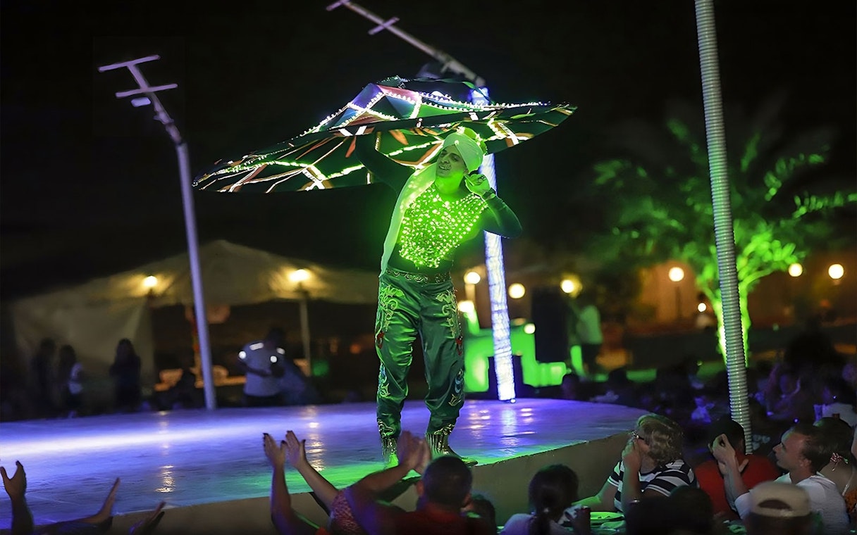 Performer in LED costume spinning on stage during Evening Red Dune Desert Safari with BBQ Buffet Dinner.