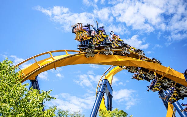 Roller coaster at Six Flags Great America with riders on a loop under a blue sky.
