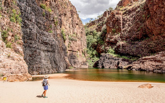 Hiker exploring rocky gorge and waterhole in Top End, Australia.