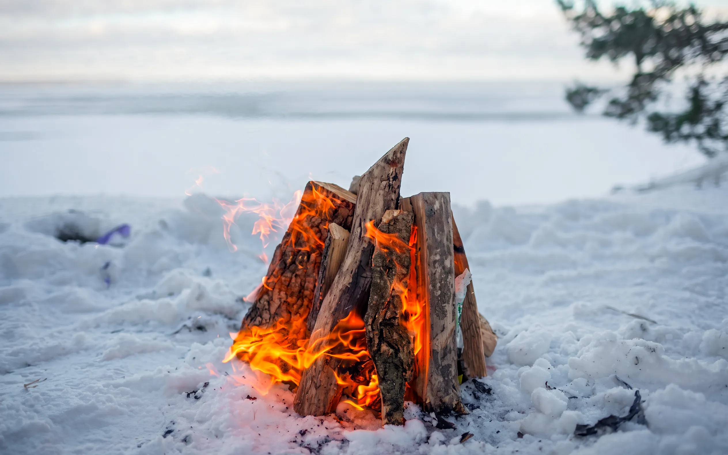 Campfire burning on snowy landscape during snowmobile safari in Rovaniemi.