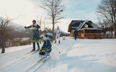 Skiers enjoying Snow and Fire Night experience near a snowy cabin.