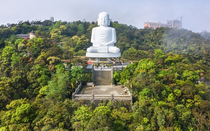 Buddha statue on Ba Na Hills, Vietnam, surrounded by lush greenery and mist.