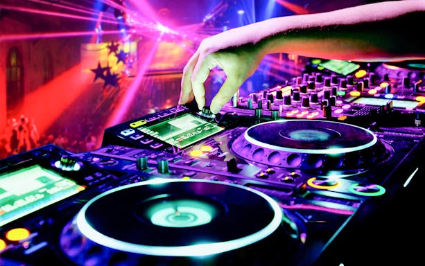 DJ mixing music on a cruise during Vivid Sydney festival with colorful lights.