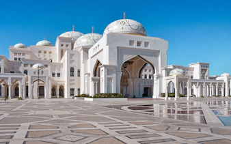 Abu Dhabi's Qasr Al Watan palace with intricate domes and arches on a clear day.
