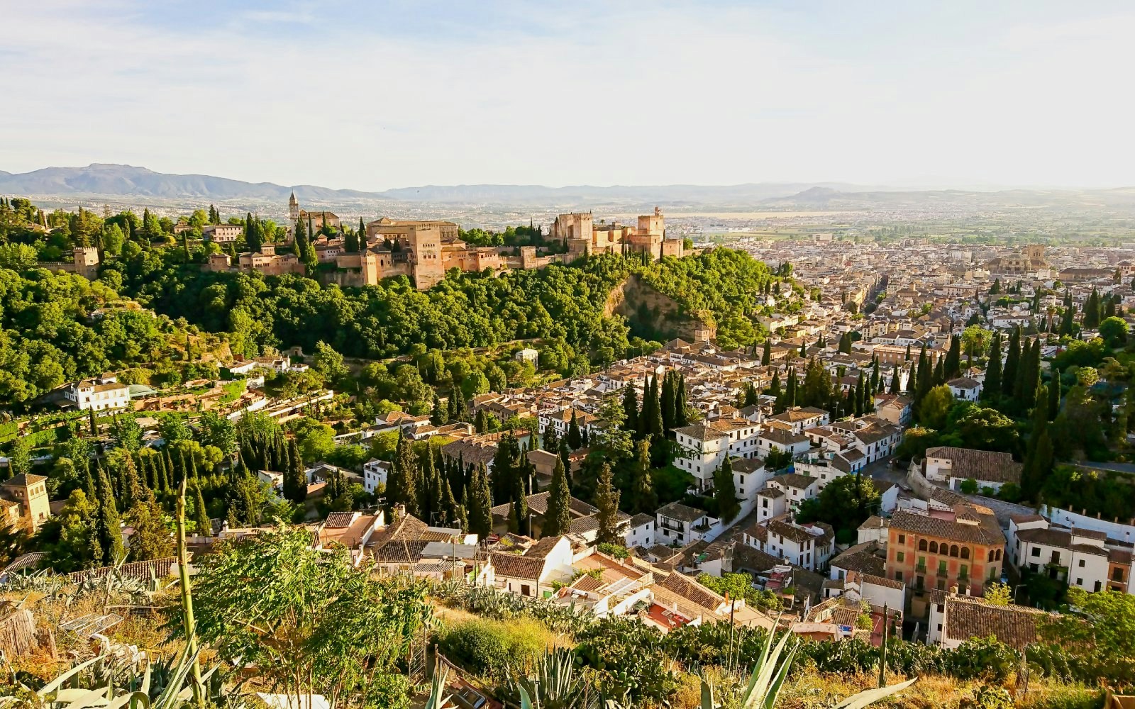 Alhambra view from Sacromonte neighborhood, Granada, with cityscape and greenery.