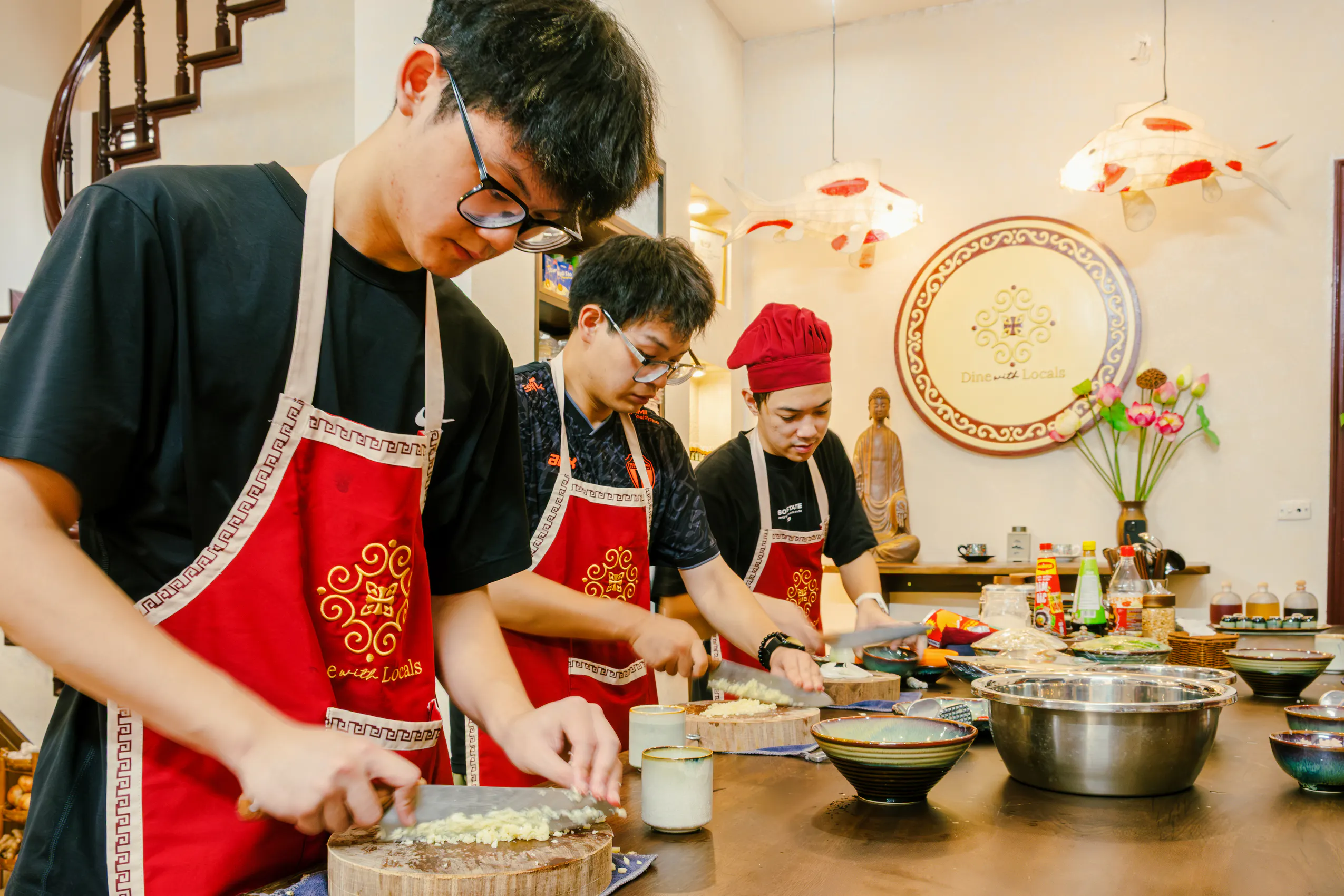 Participants preparing ingredients in a Hanoi vegan cooking class, wearing aprons and chopping vegetables.