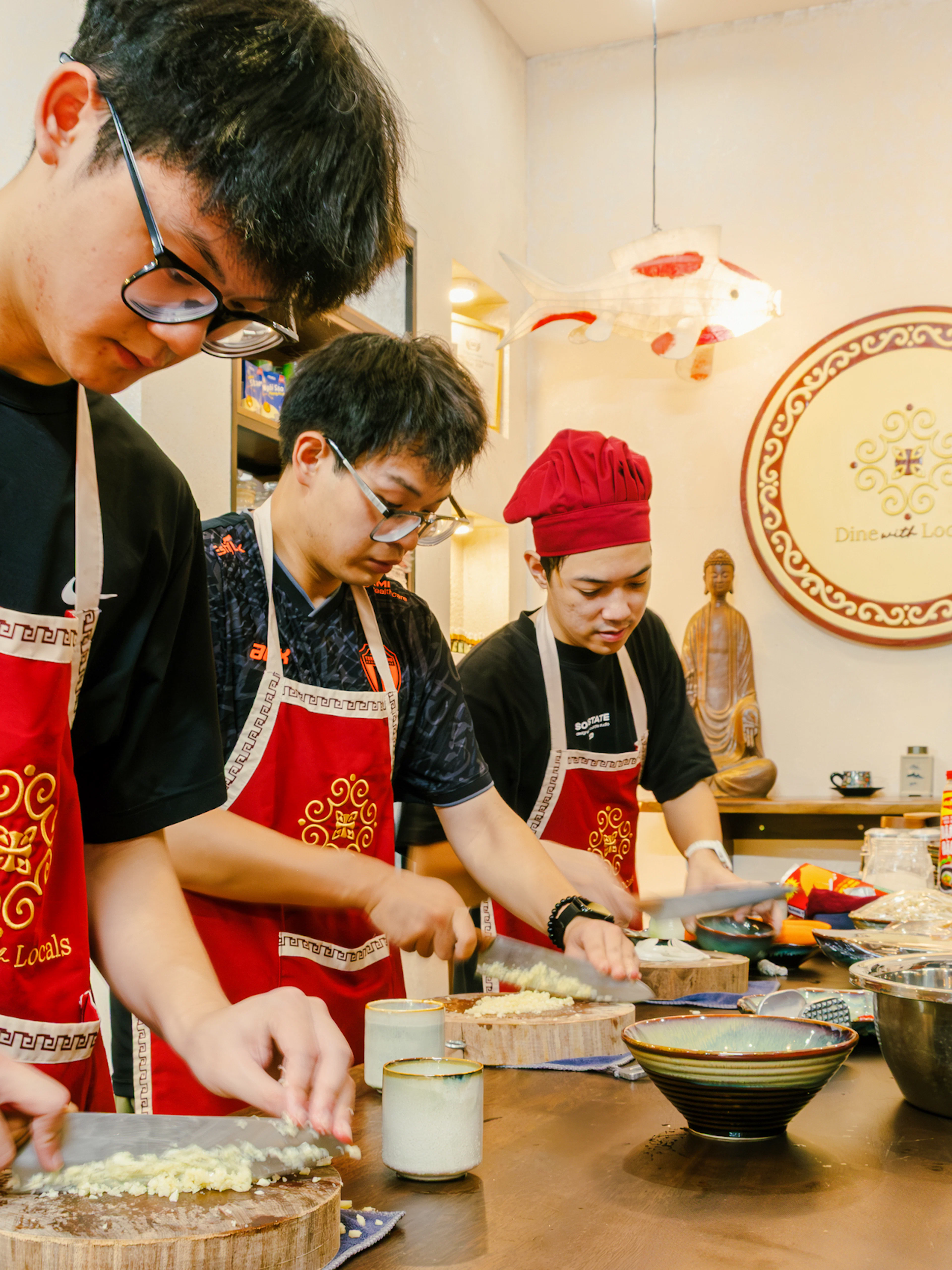 Participants preparing ingredients in a Hanoi vegan cooking class, wearing aprons and chopping vegetables.