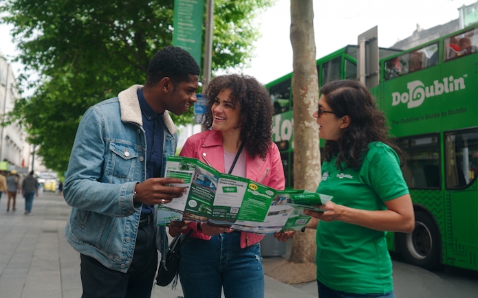 Friends using a map for a hop-on hop-off bus tour in Dublin.