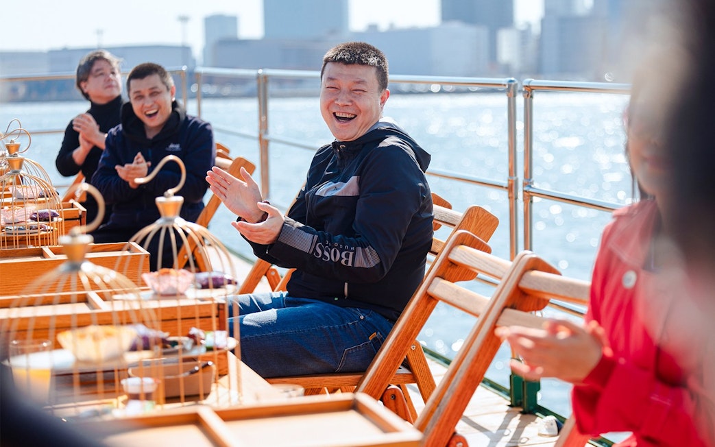 Tourists clapping and enjoying on deck of Yakatabune Cruise in Tokyo Bay.