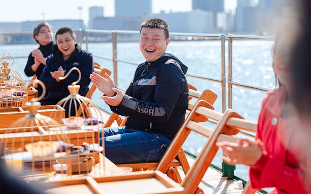 Tourists clapping and enjoying on deck of Yakatabune Cruise in Tokyo Bay.