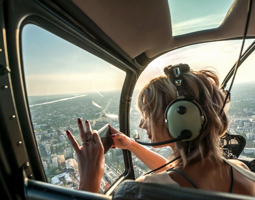 Guest photographing cityscape from helicopter tour.