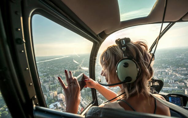 Guest photographing cityscape from helicopter tour.