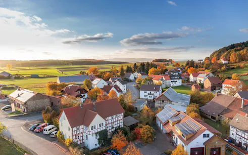 Aerial view of a rural village with red-roofed houses and autumn foliage near Plitvice Lakes.