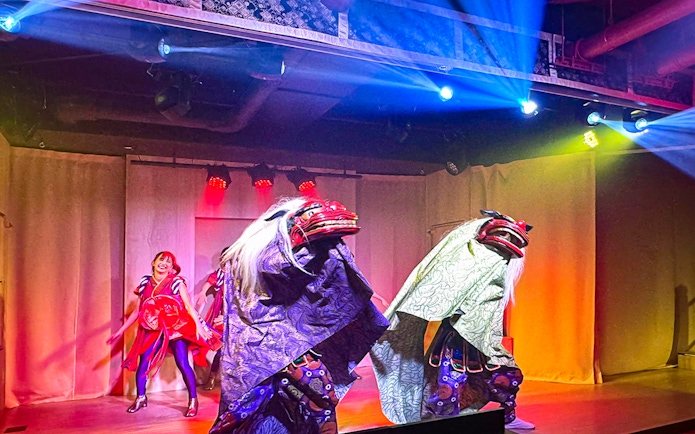 Japanese performers in traditional costumes on stage at a cabaret theatre in Tokyo.