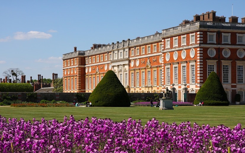 Hampton Court Palace with gardens and purple flowers in London.