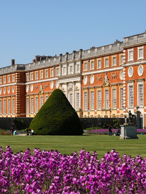 Hampton Court Palace with gardens and purple flowers in London.