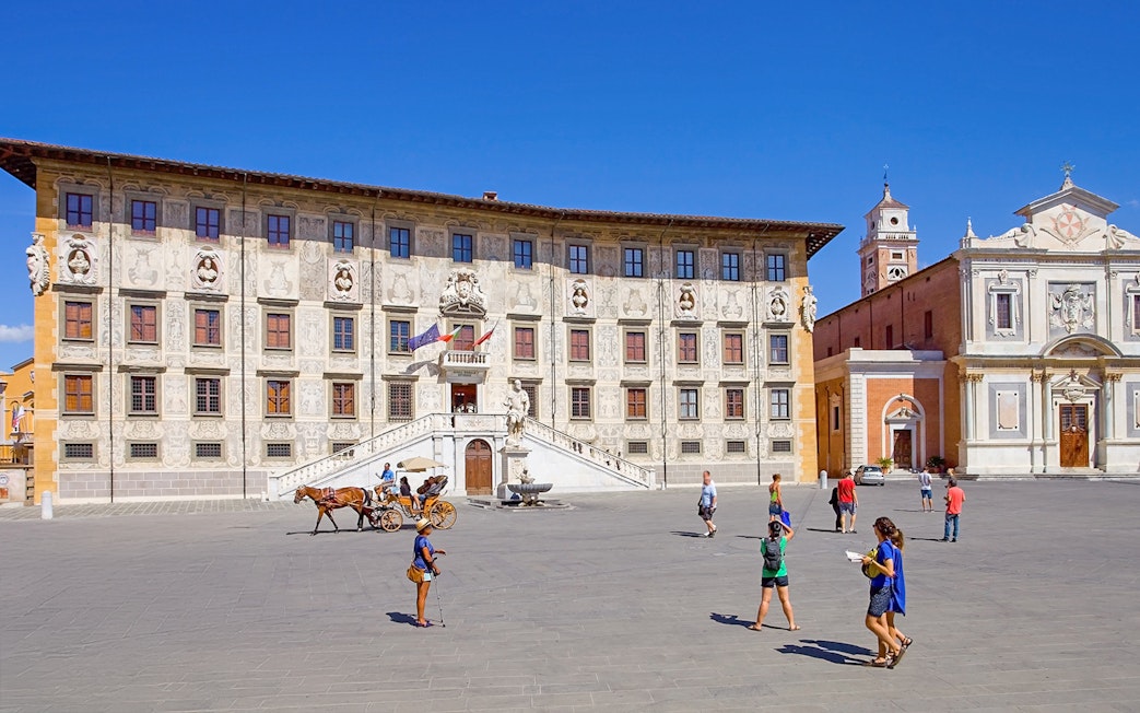 Scuola Normale Superiore at Piazza dei Cavalieri, Pisa, with tourists and a horse-drawn carriage.