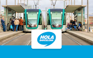 Trams at a Barcelona station with passengers boarding, Hola Barcelona logo displayed.