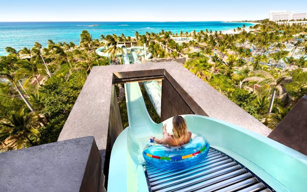 Person on water slide at Atlantis Aquaventure, Nassau, Bahamas with ocean view.