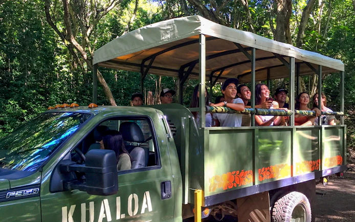 Tourists on an open-air truck during the Jurassic Adventure Tour at Kualoa Ranch, Hawaii.