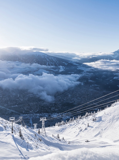 Nordkettenbahn Cable Car ascending snowy mountain with panoramic view of Innsbruck, Austria.