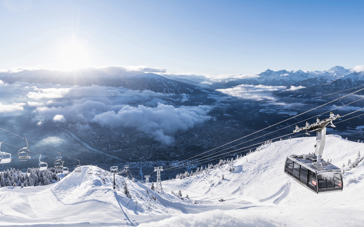Nordkettenbahn Cable Car ascending snowy mountain with panoramic view of Innsbruck, Austria.