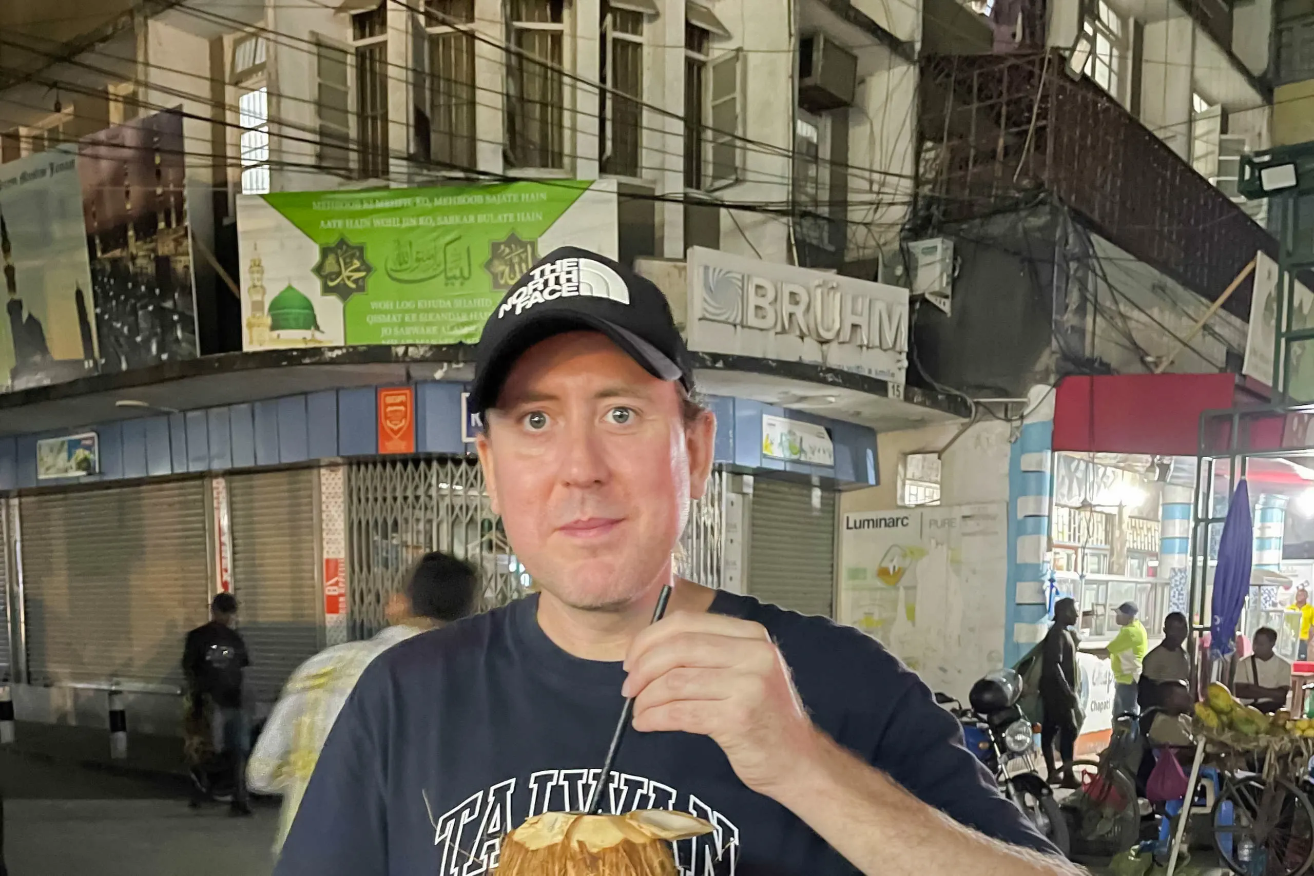 Man enjoying fresh coconut drink on a street food tour in Dar es Salaam, Tanzania.