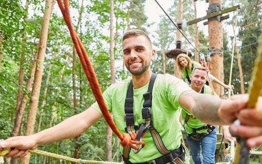 Team climbing high ropes course in forest.