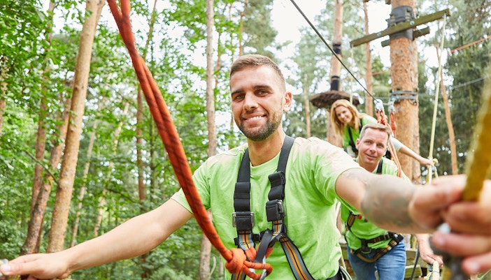 Man and his team climbing in the high ropes