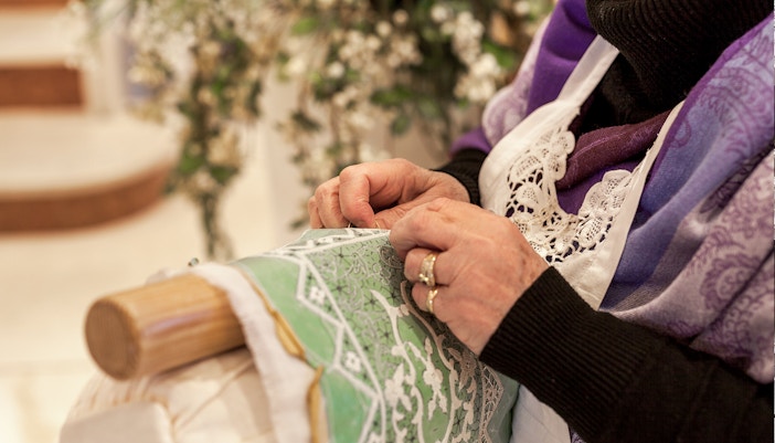 Lady embroidering lace on Burano during Venice full-day guided tour.