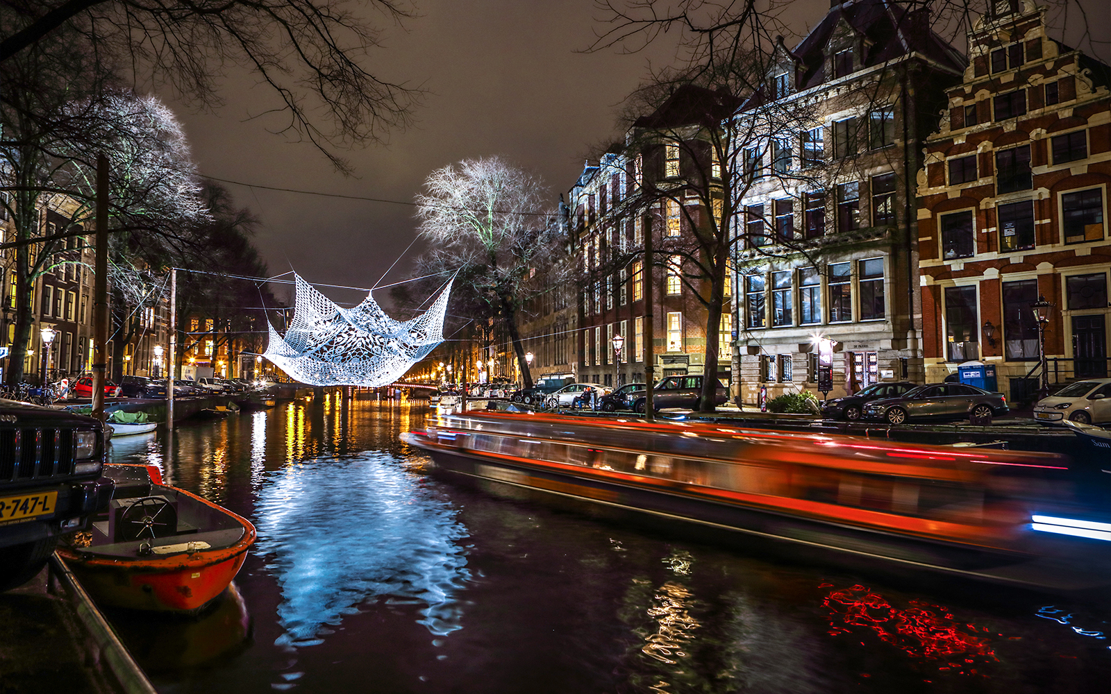 Amsterdam canal with illuminated art installation during Light Festival cruise.