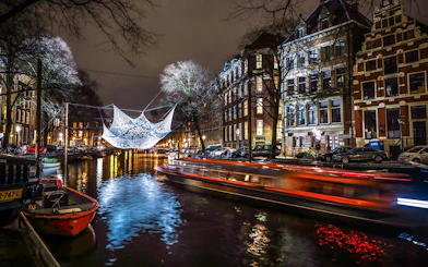 Amsterdam canal with illuminated art installation during Light Festival cruise.