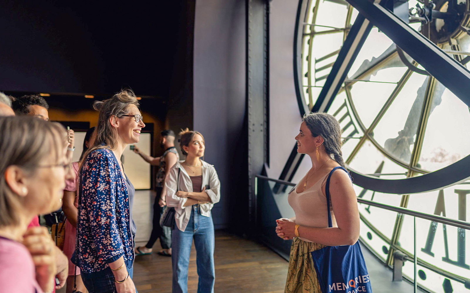 Visitors viewing an exhibition at Orsay Museum, Paris, with famous artworks displayed.