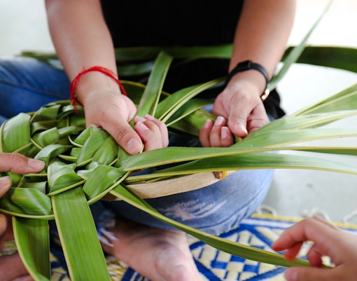 Hands weaving coconut leaves at a workshop in Hoi An.