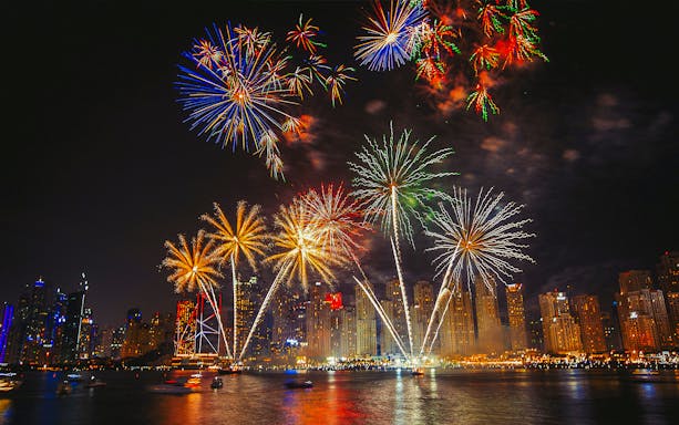Dubai skyline with vibrant New Year 2024 fireworks over the waterfront.