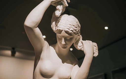 Sculpture of a woman adjusting her hair, featured in Alexander McQueen Mind, Mythos, Muse exhibit.