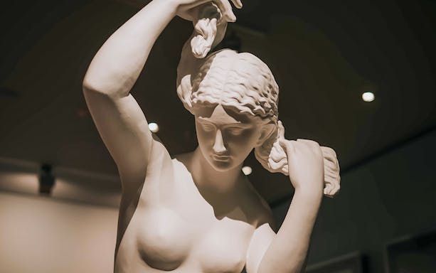 Sculpture of a woman adjusting her hair, featured in Alexander McQueen Mind, Mythos, Muse exhibit.
