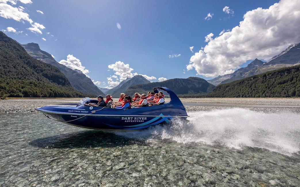 Jet boat on Dart River with tourists enjoying Funyak adventure in New Zealand.