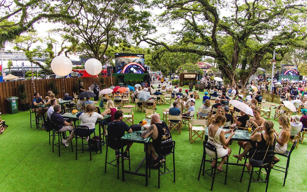 Patrons watching race action on screen at outdoor venue, Waterside.