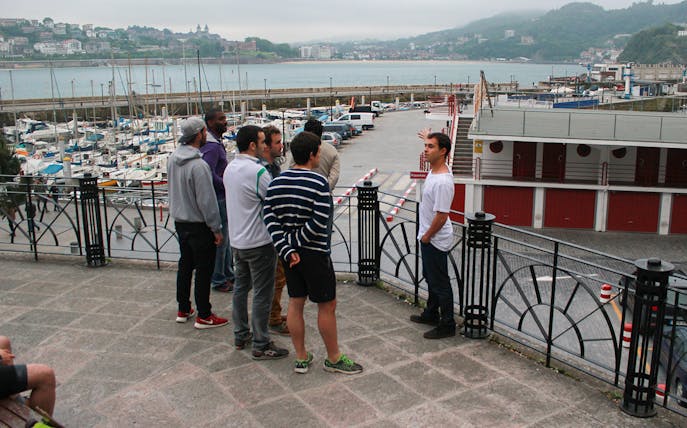 Group on a guided walking tour overlooking San Sebastian marina.