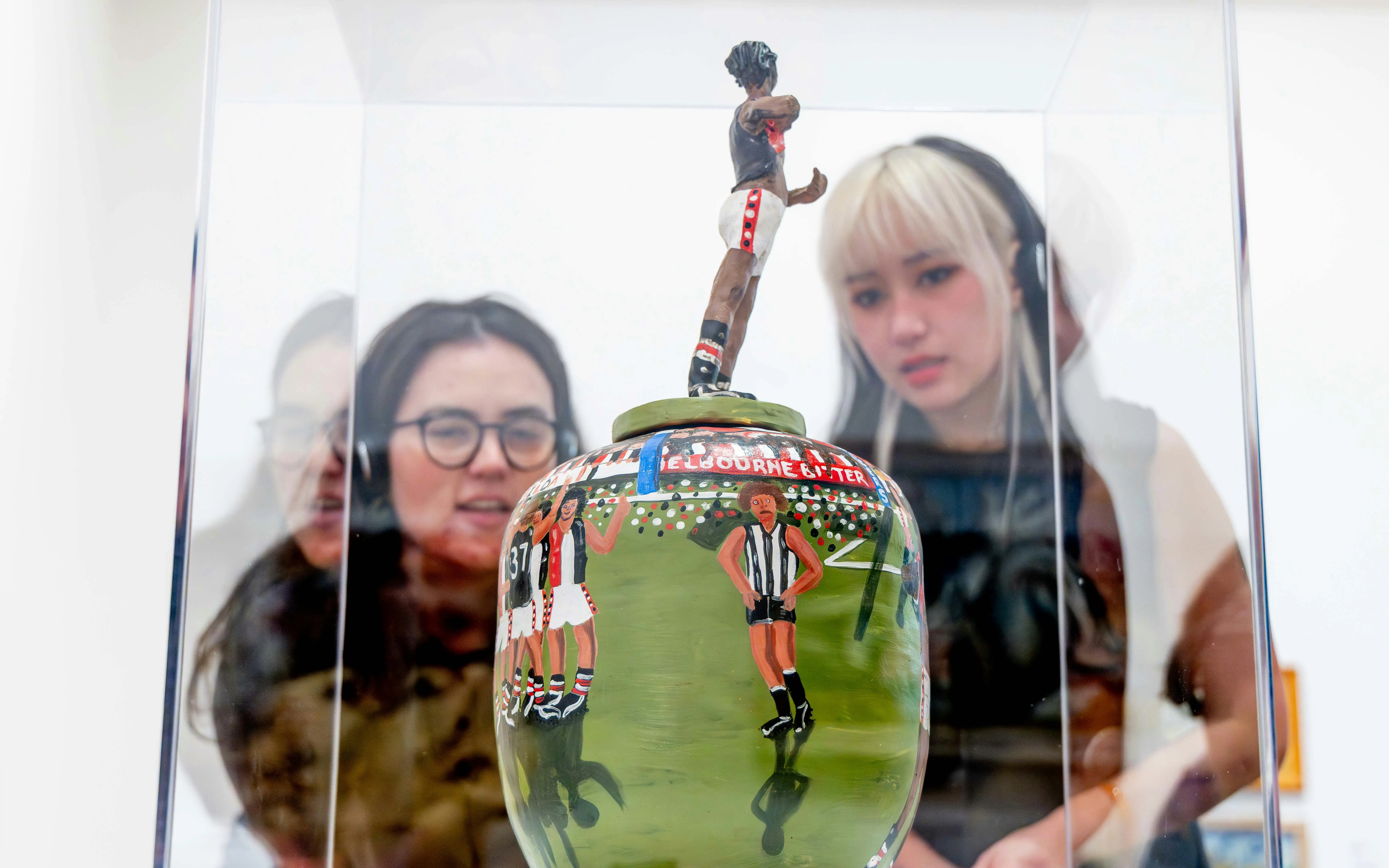 Visitors viewing a painted ceramic vase at the National Gallery of Victoria.