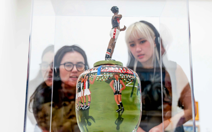 Visitors viewing a painted ceramic vase at the National Gallery of Victoria.