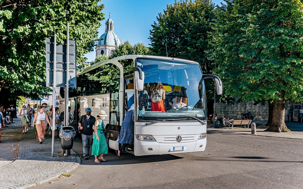 Tourists boarding a bus for a day trip to Lake Como, Bellagio, and Lugano.