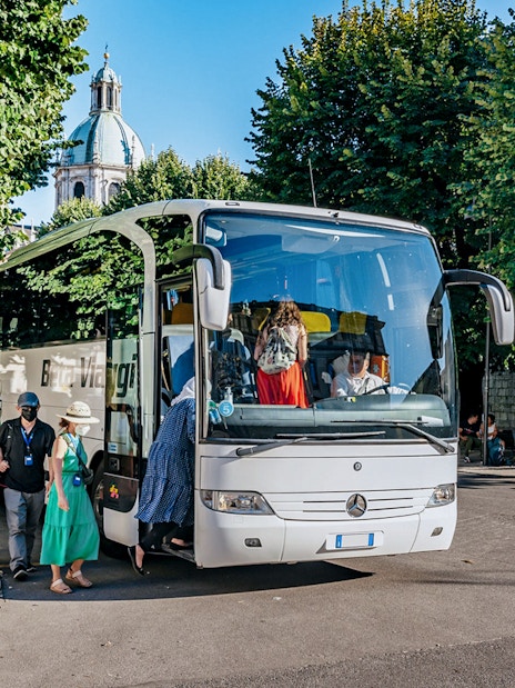Tourists boarding a bus for a day trip to Lake Como, Bellagio, and Lugano.