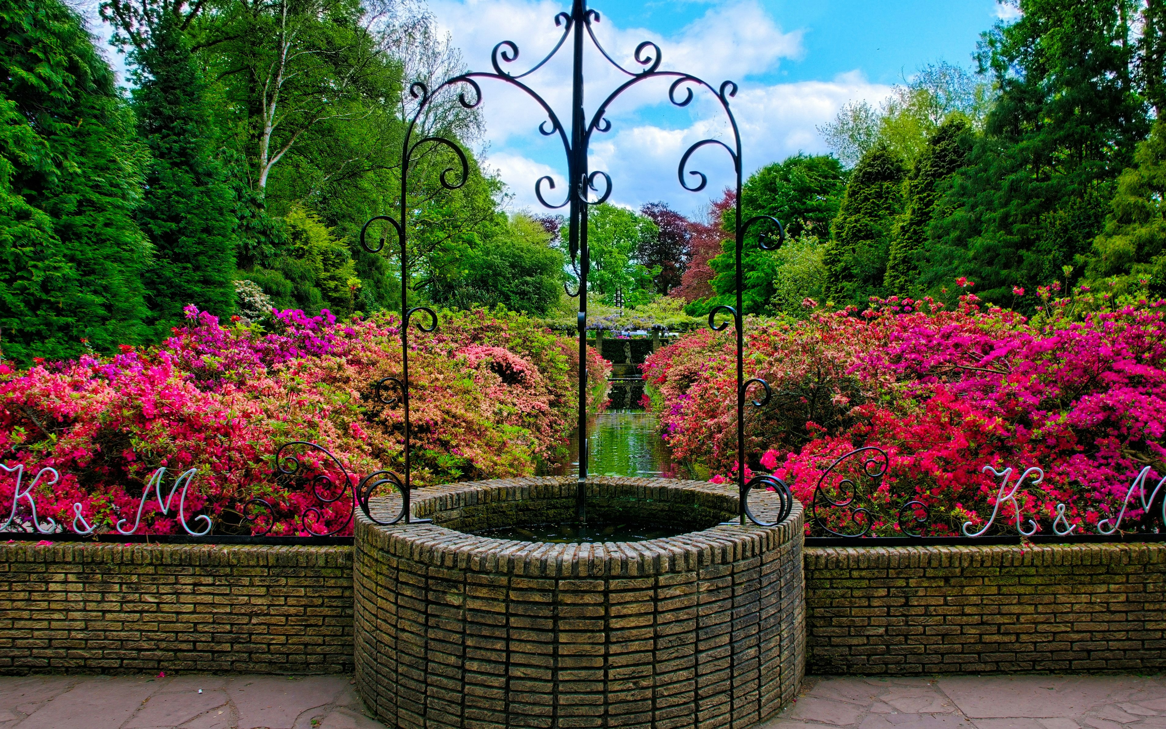 Well surrounded by pink azalea flowers in Keukenhof Castle garden.