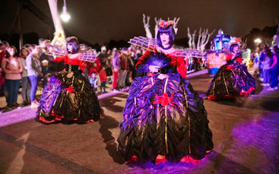 Performers in Halloween costumes at PortAventura Park parade at night.